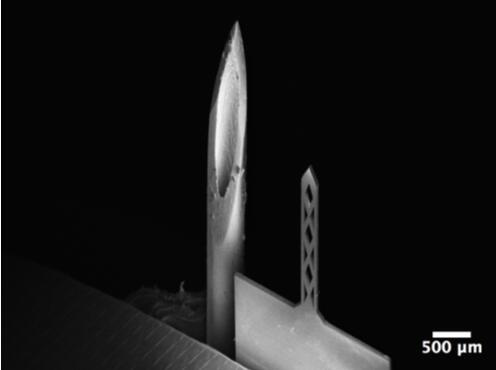 開孔鈦基微針（200um寬，50um厚，1500um長）和26G皮下注射針（外徑464um）對比的掃描電子顯微鏡照片